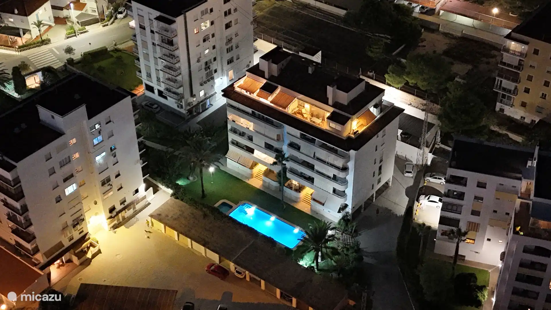 Nuestro complejo de noche: piscina y jardín bien iluminados, bellamente visibles desde el aire para un ambiente encantador