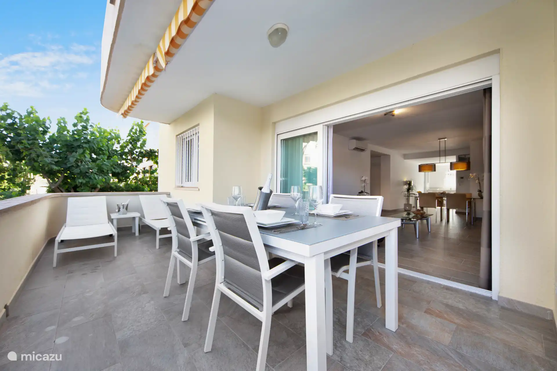 Terraza privada con tumbonas, mesa de comedor y vistas a la piscina