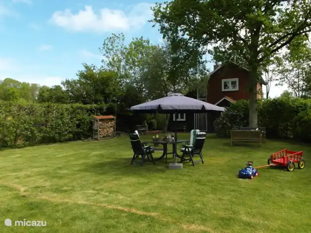 Cotule | Pays-Bas, Zélande, Oostkapelle - maison de vacances Grand jardin ensoleillé avec mobilier et barbecue.
Une charrette à bras pour les petits enfants.