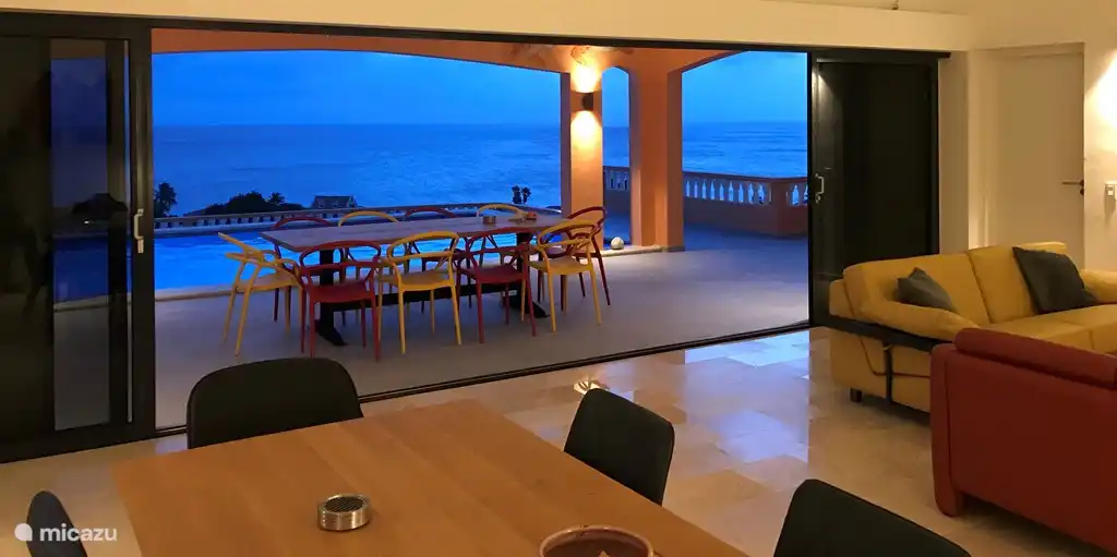 Großes Wohnzimmer mit großen Schiebetüren zur Terrasse mit Pool, Blick auf das Meer