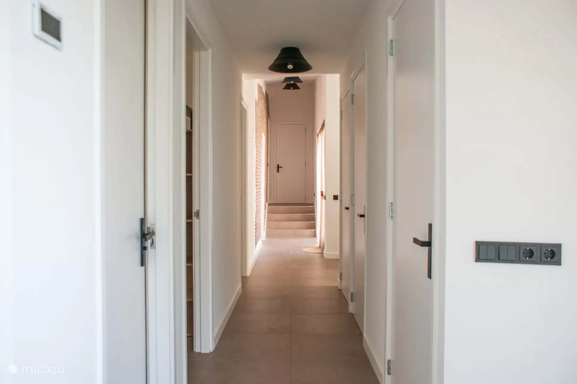 From the hallway you reach three bedrooms, a separate toilet, the bathroom and through two open passages the kitchen and living room on the first floor.