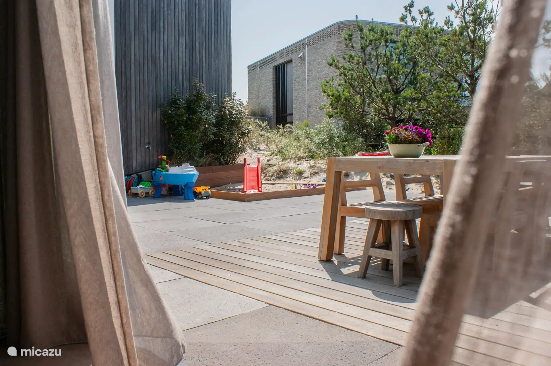Terrace with large teak table, parasol, sandpit with slide and outdoor toys.