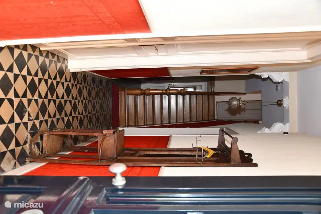 La entrada, a la izquierda la puerta de la sala de &#233;poca, la segunda puerta de la cocina y la puerta trasera del sal&#243;n. A la derecha est&#225; el primer ba&#241;o y la habitaci&#243;n con la lavadora. Debajo de las escaleras est&#225; la entrada a la bodega.