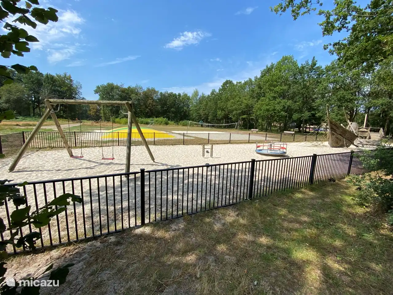The playground at the park has a swing, a seesaw, a merry-go-round and an air trampoline