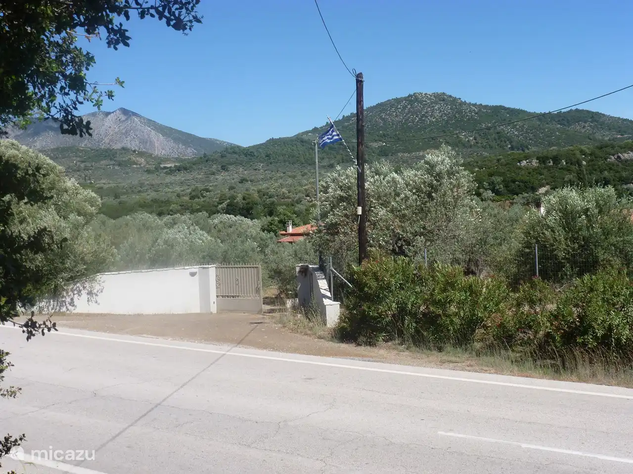 le portail d'entrée avec drapeau sur le poteau téléphonique qui sert de repère.