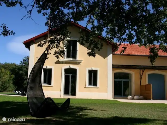 Castillo Portos en el sur de Francia en Francia, Tarn, Cahuzac - casa vacacional Frente de la casa de vacaciones con dos acogedores columpios adosados a los viejos robles en el jardín