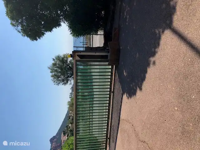 Parkeerplaats achter hek aan de weg, naast het appartement.