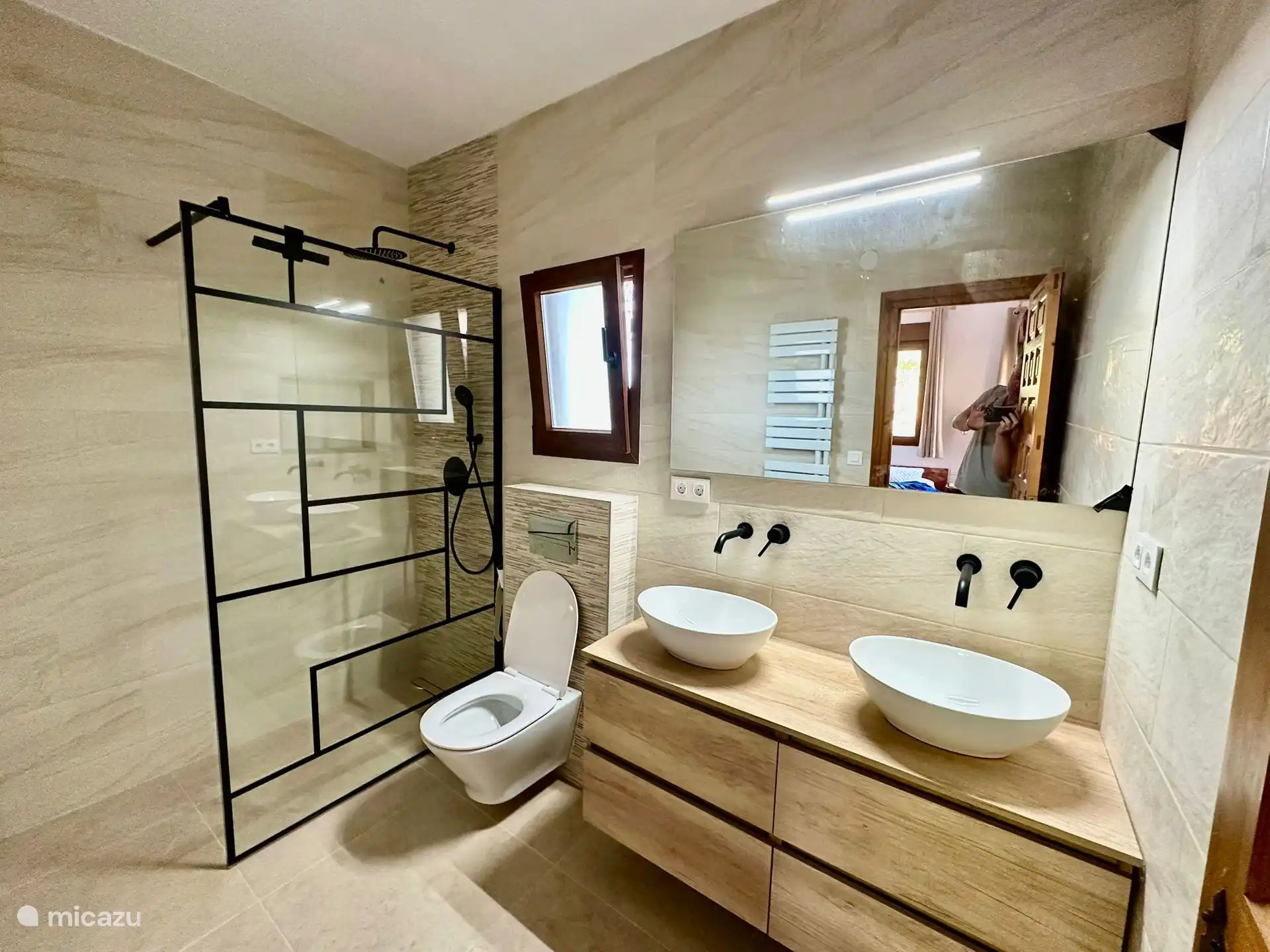 Salle de bain attenante avec double lavabo, deuxième toilette, douche à l’italienne et radiateur à serviettes.