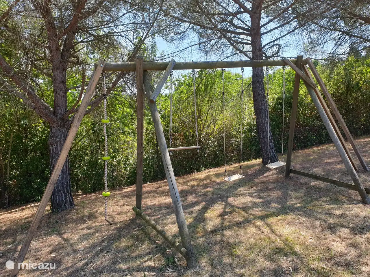 Parque infantil con columpios y casita de escalada.