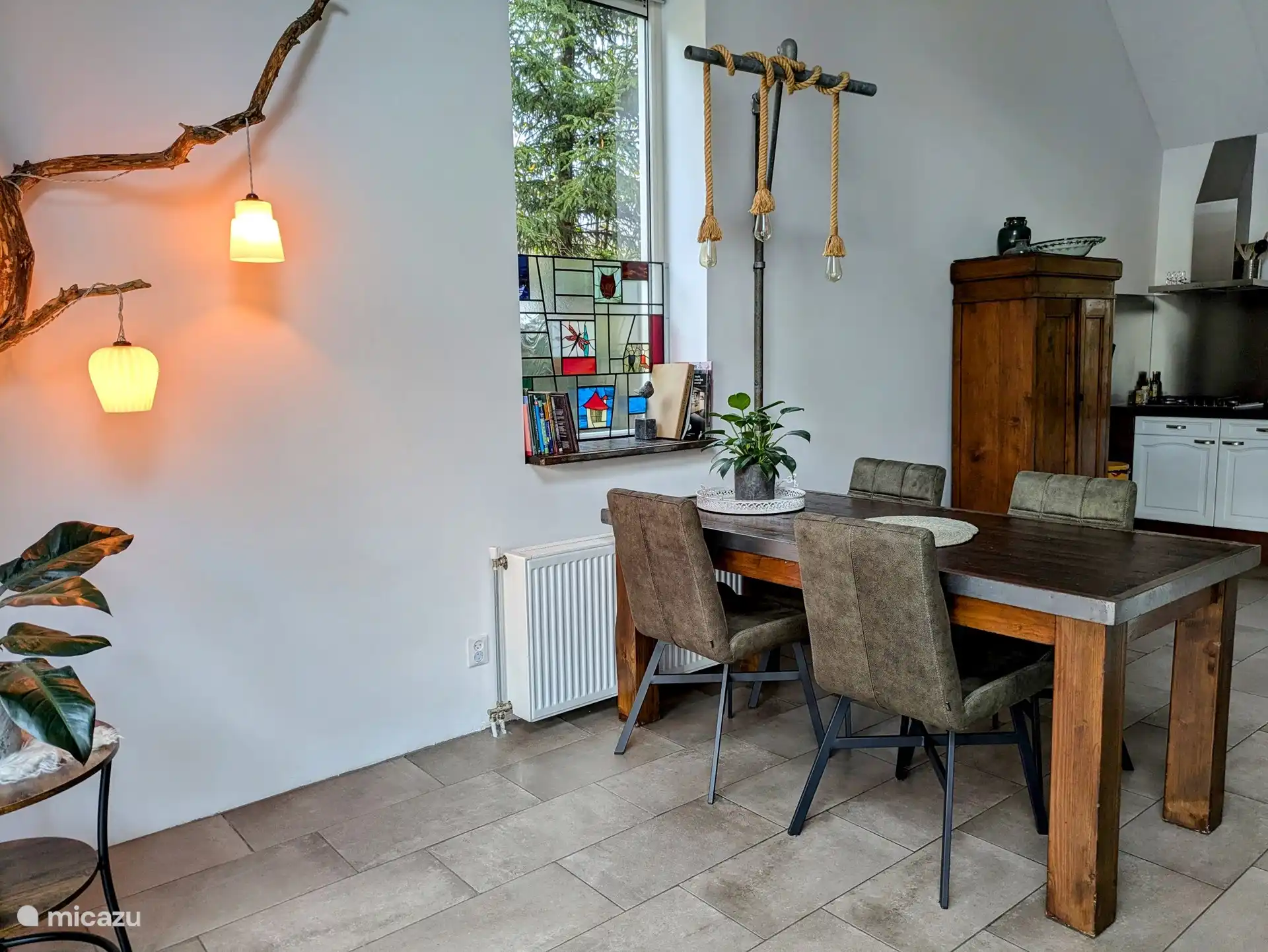 Über dem Esstisch hängt die Beleuchtung an einem Gerüstrohr. Zusammen mit dem Esstisch wirkt dieser Spot robust. Hier können Sie zusammen essen oder ein Spiel spielen. Die Spiele sind im braunen Schrank in der Küche.