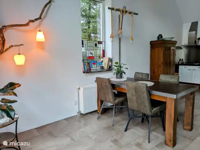 BuitenGewoon huren in Nederland, Drenthe, Westerbork - vakantiehuis Boven de eettafel hangt de verlichting aan een steigerbuis. Samen met de eettafel heeft dit plekje een robuuste uitstraling. Hier kunt u gezellig samen eten of een spelletje spelen. De spelletjes liggen in de bruine kast in de keuken.