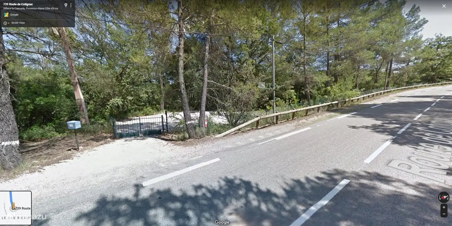 Das Eingangstor mit einer langen Auffahrt, die abfällt. Das Haus ist komplett von der Straße abgeschirmt.