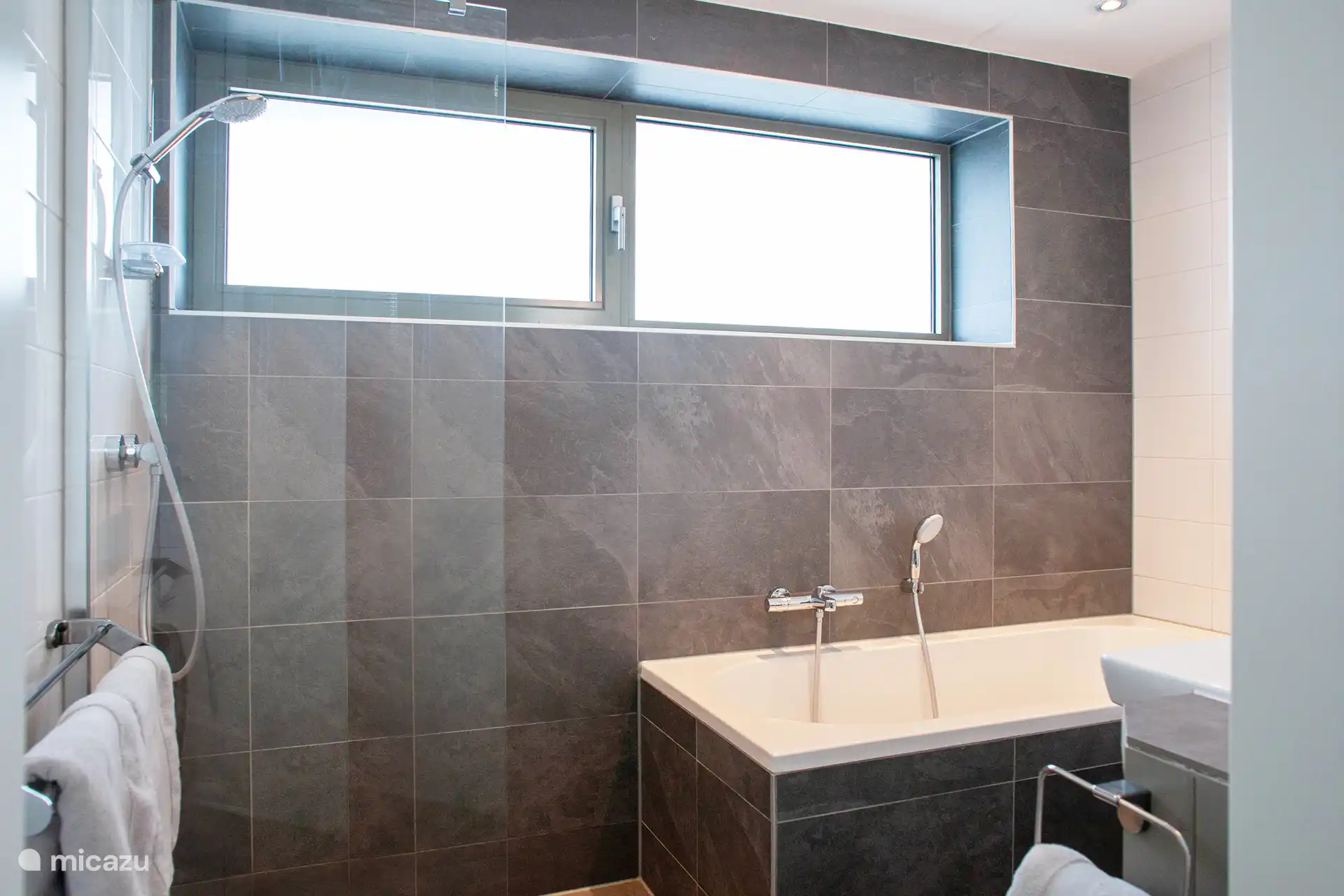 Badezimmer im Erdgeschoss mit Badewanne, Dusche, Toilette und Waschbecken.