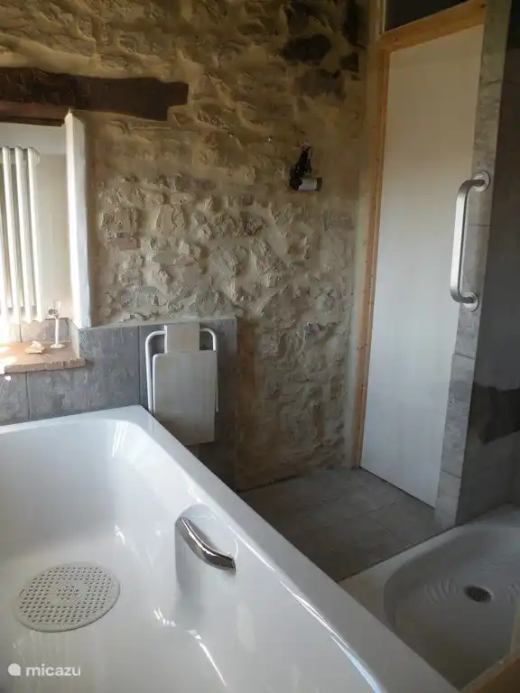 Badkamer met bad en douche en natuurstenen muur. Casa Calénc 138