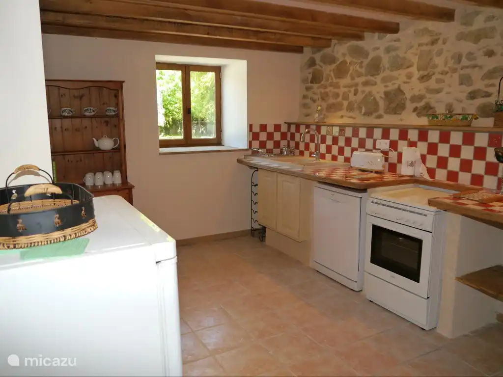 Cocina moderna totalmente equipada con lavavajillas, encimera de gas con horno eléctrico y frigorífico.