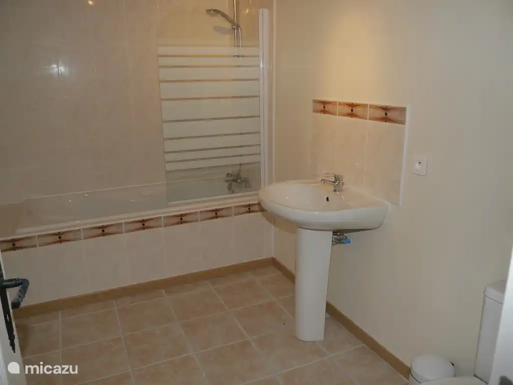 Baño en la planta baja con bañera y ducha fija, lavabo y WC. Las toallas se almacenan aquí.