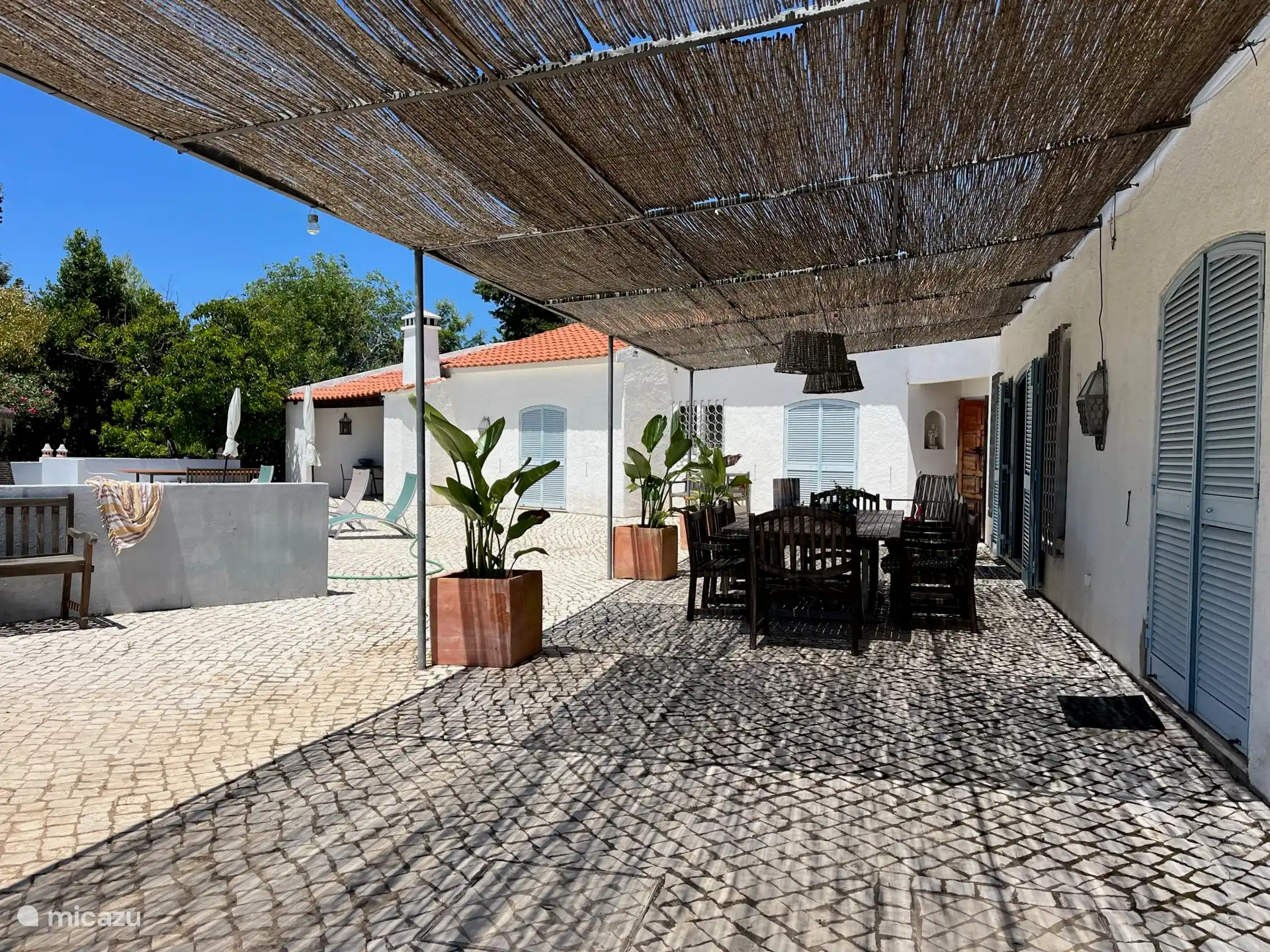 Terras met grote eettafel onder schaduwrijke overkapping