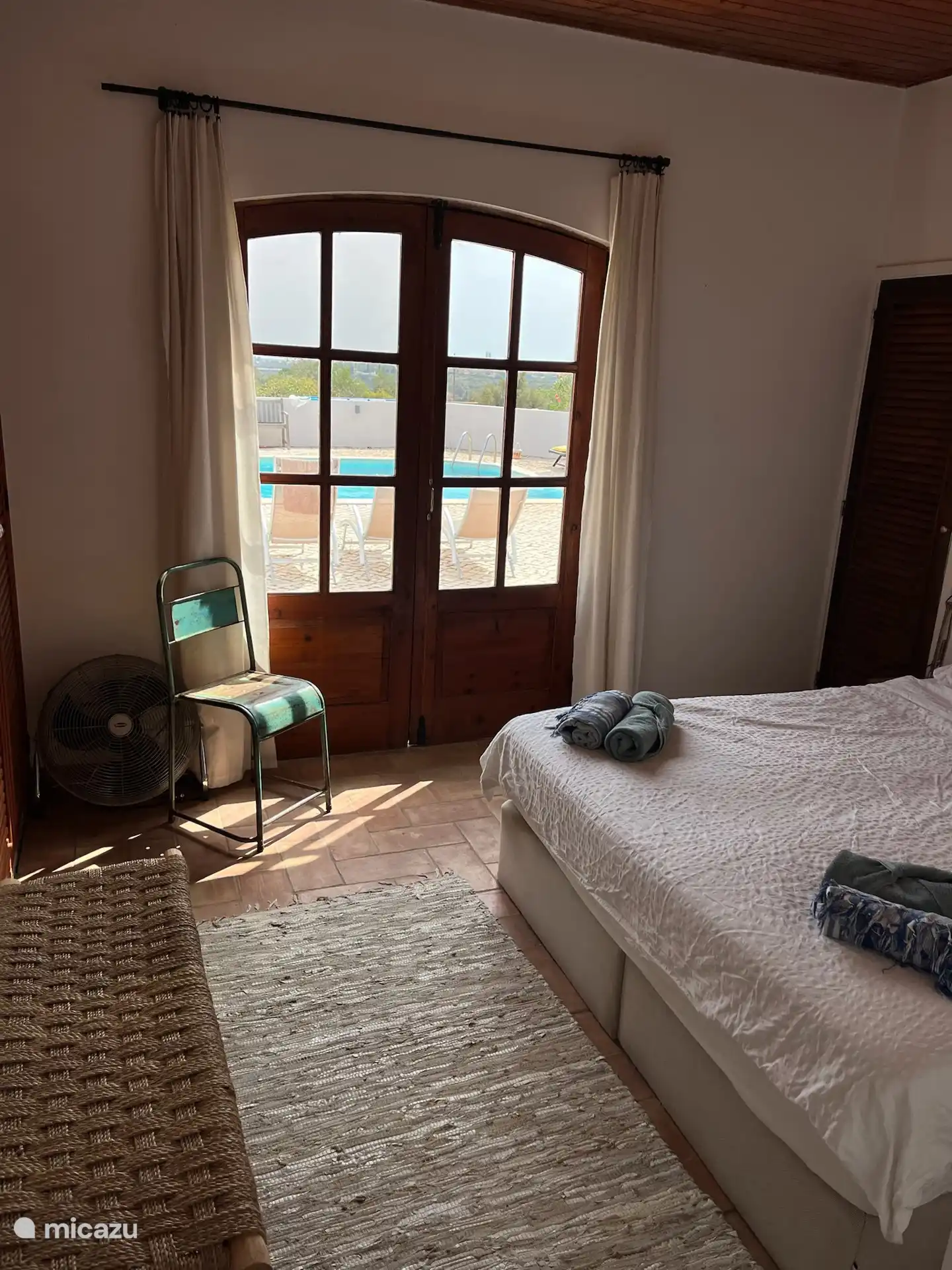 slaapkamer met openslaande deuren naar terras met zwembad