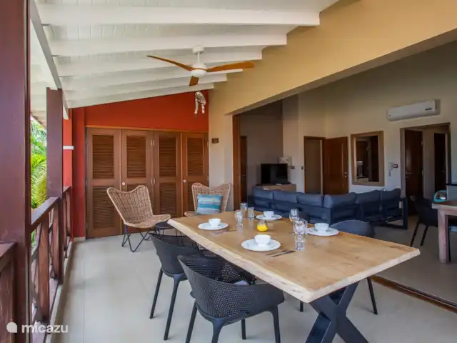Área Jan Thiel | apartamento C8 en Curazao, Banda Arriba (este), Spaanse Water - apartamento Balcón sombreado con mesa de comedor y puertas abiertas al área interior.