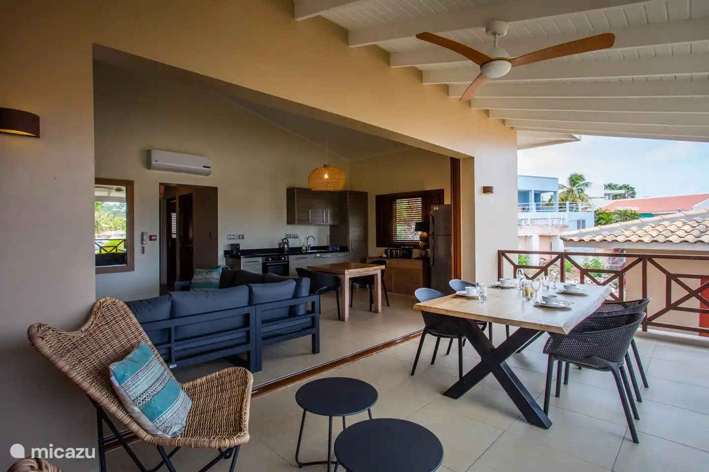 Schaduwrijk balkon met eettafel en open deuren naar binnengedeelte.