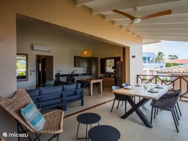 Área Jan Thiel | apartamento C8 en Curazao, Banda Arriba (este), Spaanse Water - apartamento Balcón sombreado con mesa de comedor y puertas abiertas al área interior.