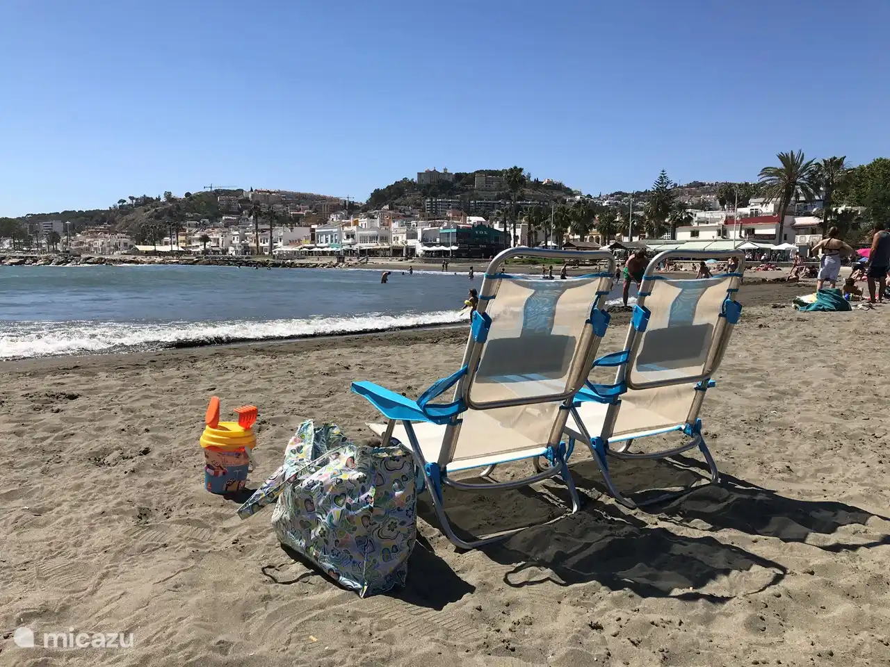 Twee strandstoeltjes, een strandtas en emmer met schepjes beschikbaar.