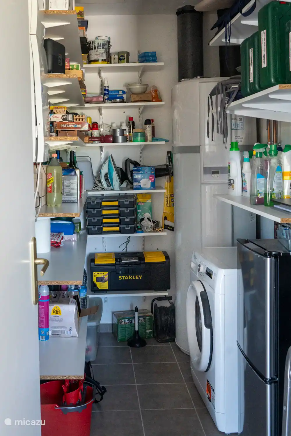 De voorraadkamer met wasmachine, een tweede koelkast met vriesvak, gereedschap, spelletjes en meer dan voldoende plek voor eigen voorraad.