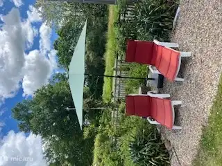 Twee ligstoelen onder parasol in een ruime tuin