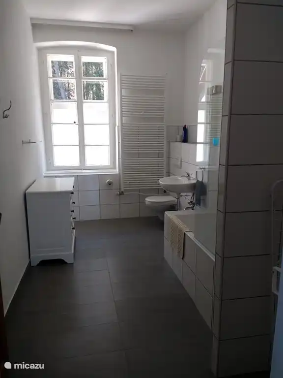 Das neue Badezimmer ist geräumig und verfügt über ein WC, ein Waschbecken, eine Dusche und eine Badewanne.