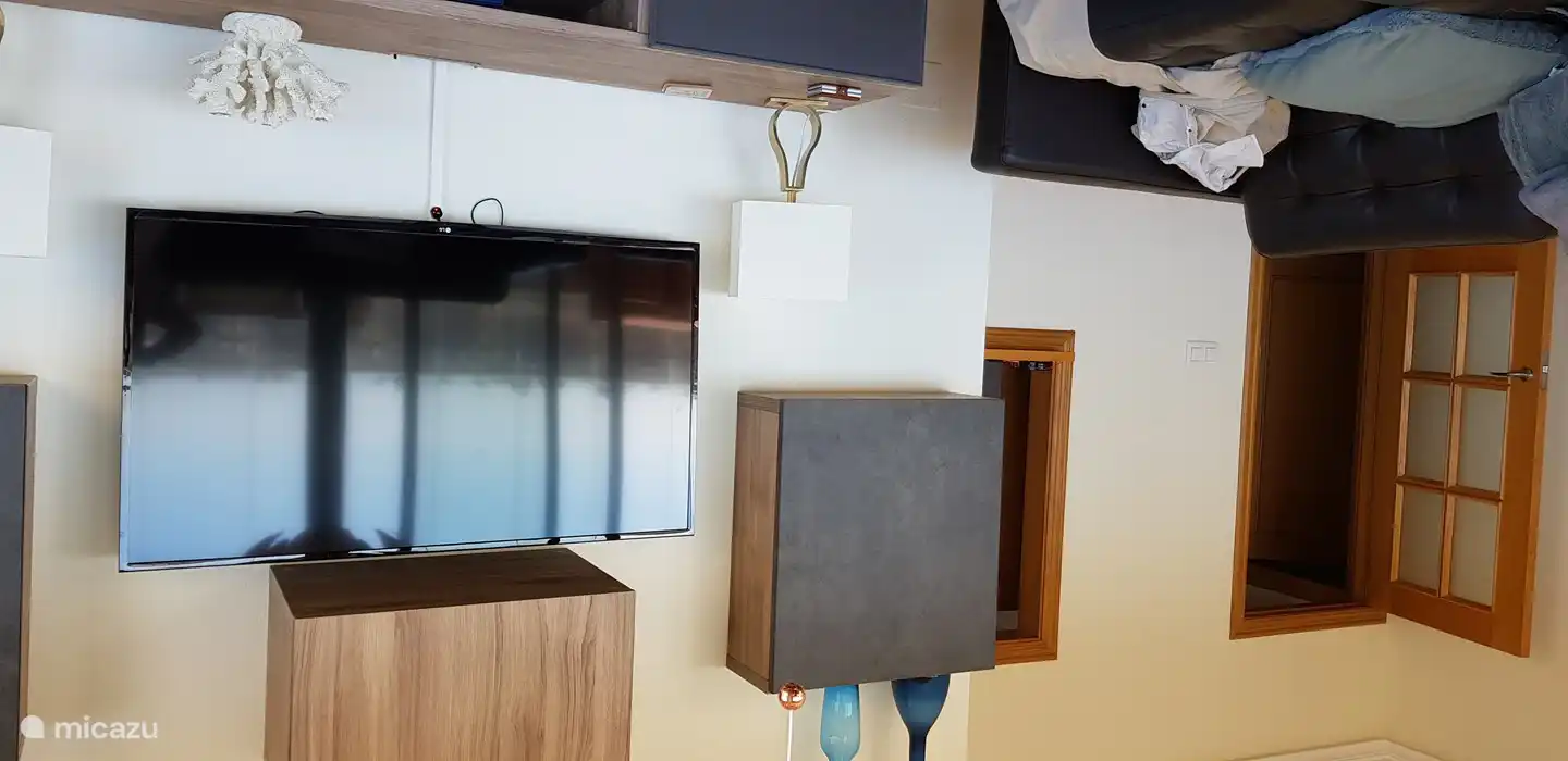 Gran pantalla de TV y vista de la abertura de paso a la cocina a la derecha de la puerta.