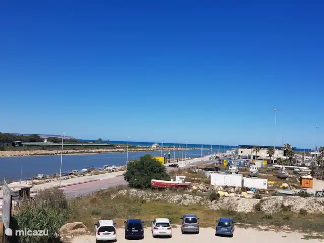 Residencial Puerto Marino en España, Costa Blanca, Guardamar del Segura - apartamento vista desde el balcón sobre el canal y el mar mediterráneo y barrera para ingresar al área del puerto. Tarifa de estacionamiento 1 euro por día. Aparcamiento cerca de la playa posible. Buen restaurante con gran terraza con vistas al puerto.