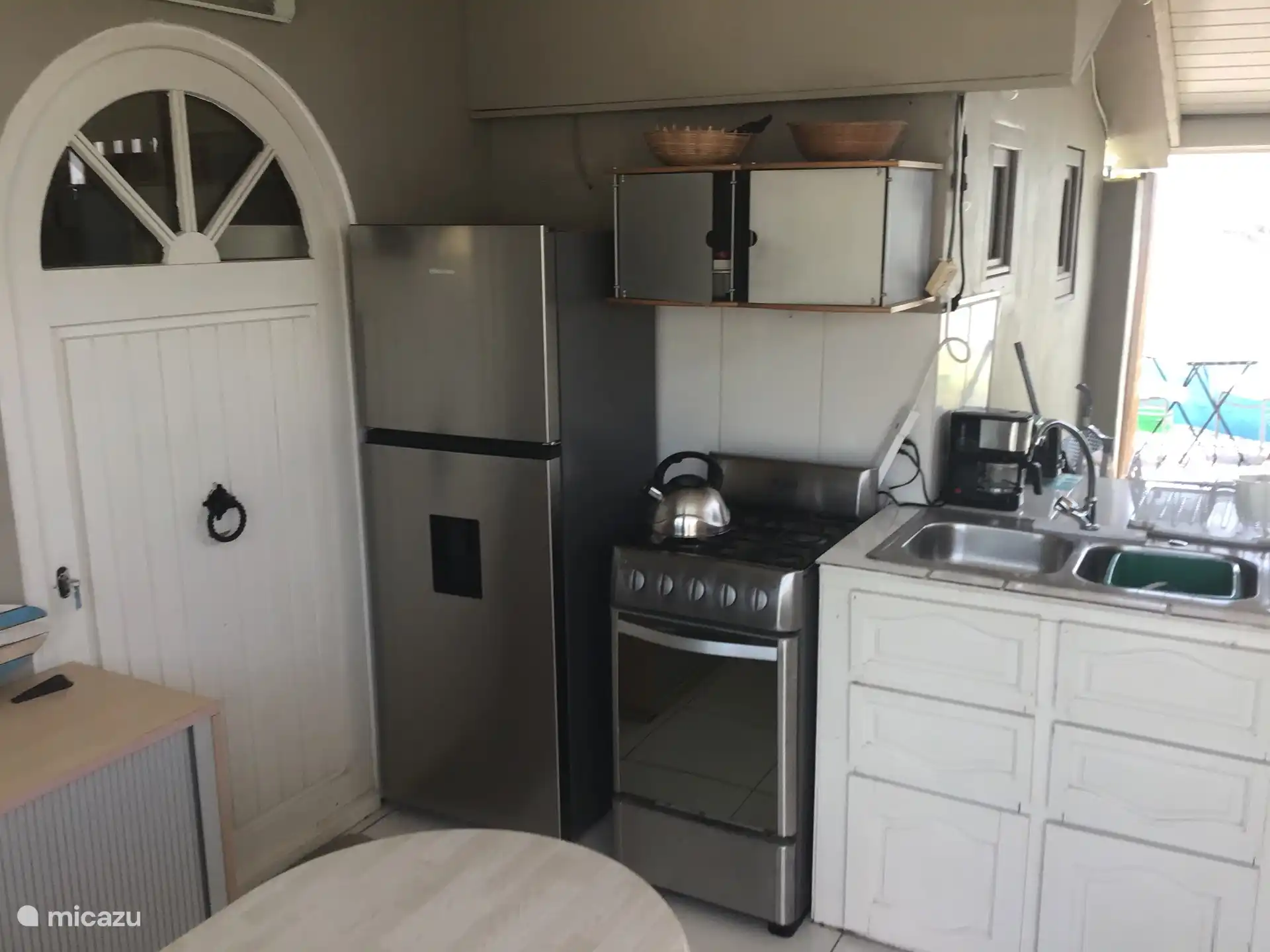 La cocina exterior cubierta con sala de estar y acceso al jardín con piscina 