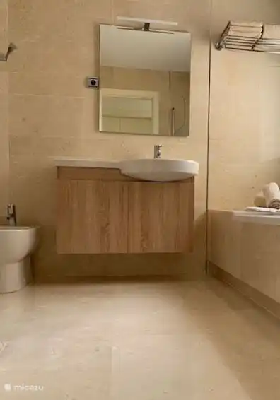 Cuarto de baño con ducha a ras de suelo y ducha de lluvia, inodoro y bidé