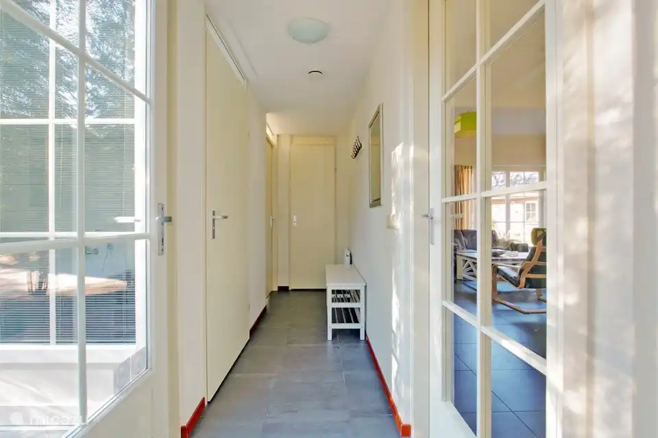 Der helle Eingang mit praktischer Schuhablage unter den Garderoben führt zum Wohnzimmer, zum Badezimmer, zu den 2 Schlafzimmern im Erdgeschoss, zur Toilette und zur Theke.