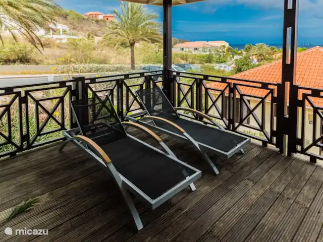 Vue sur l'océan 20 | Blue Bay | | Curaçao, Curaçao-Centre, Blue Bay - villa Pour le summum du luxe, deux belles chaises longues sur la véranda pour profiter de votre vue dans un cadre extrêmement relaxant. En plus de ces chaises, vous trouverez également une table à manger spacieuse pouvant accueillir 6 personnes.
