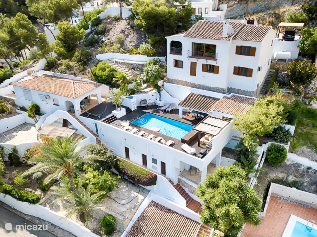 Haupthaus, Poolterrasse mit Außenküche, Gästehaus, Auffahrt und Carport.