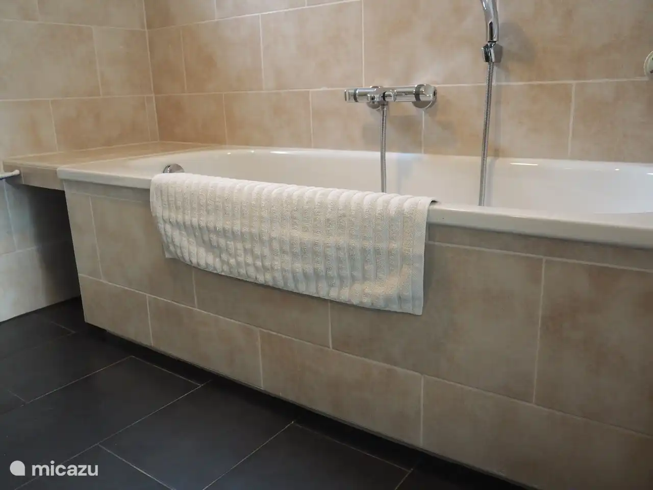 La salle de bain spacieuse dispose d'une baignoire avec repose-pieds, d'une douche à l'italienne et d'un lavabo avec mitigeur