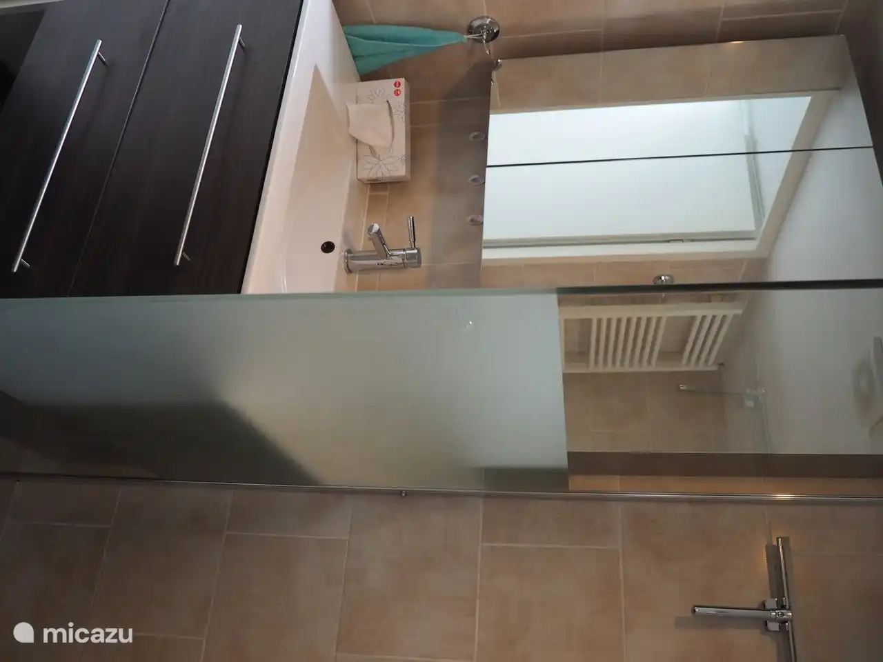 Lavabo spacieux avec armoire miroir à côté de la douche avec entrée basse.