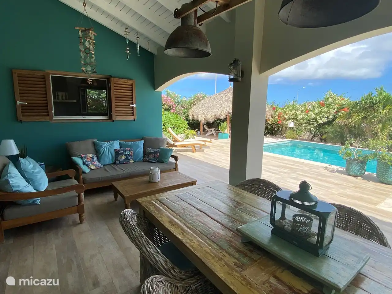 Table à manger sur porche avec coin salon en arrière-plan et vue sur la piscine