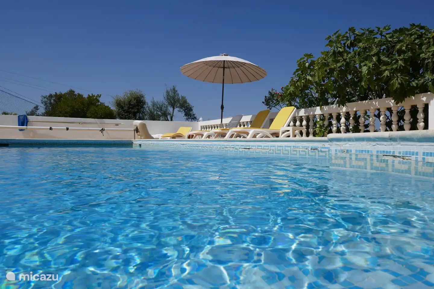 Vista a la amplia piscina, tumbonas y sombrillas disponibles, así como aseo 