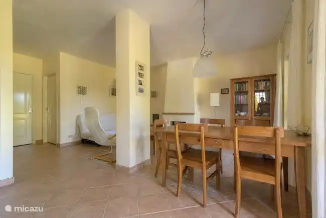 El salón con comedor para 5. Hay una estantería llena de libros y juegos para todos los gustos. Hay mosquiteros en las puertas del patio.