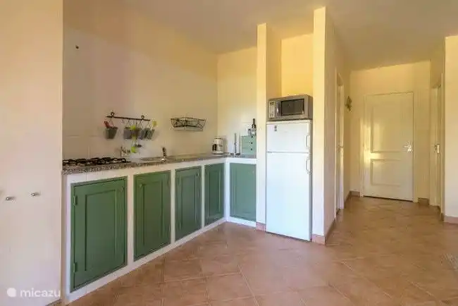 La cocina totalmente equipada está construida en estilo antiguo: como solían verse las cocinas en Italia. Miras un espacioso vestidor a la derecha. Práctico para las maletas.