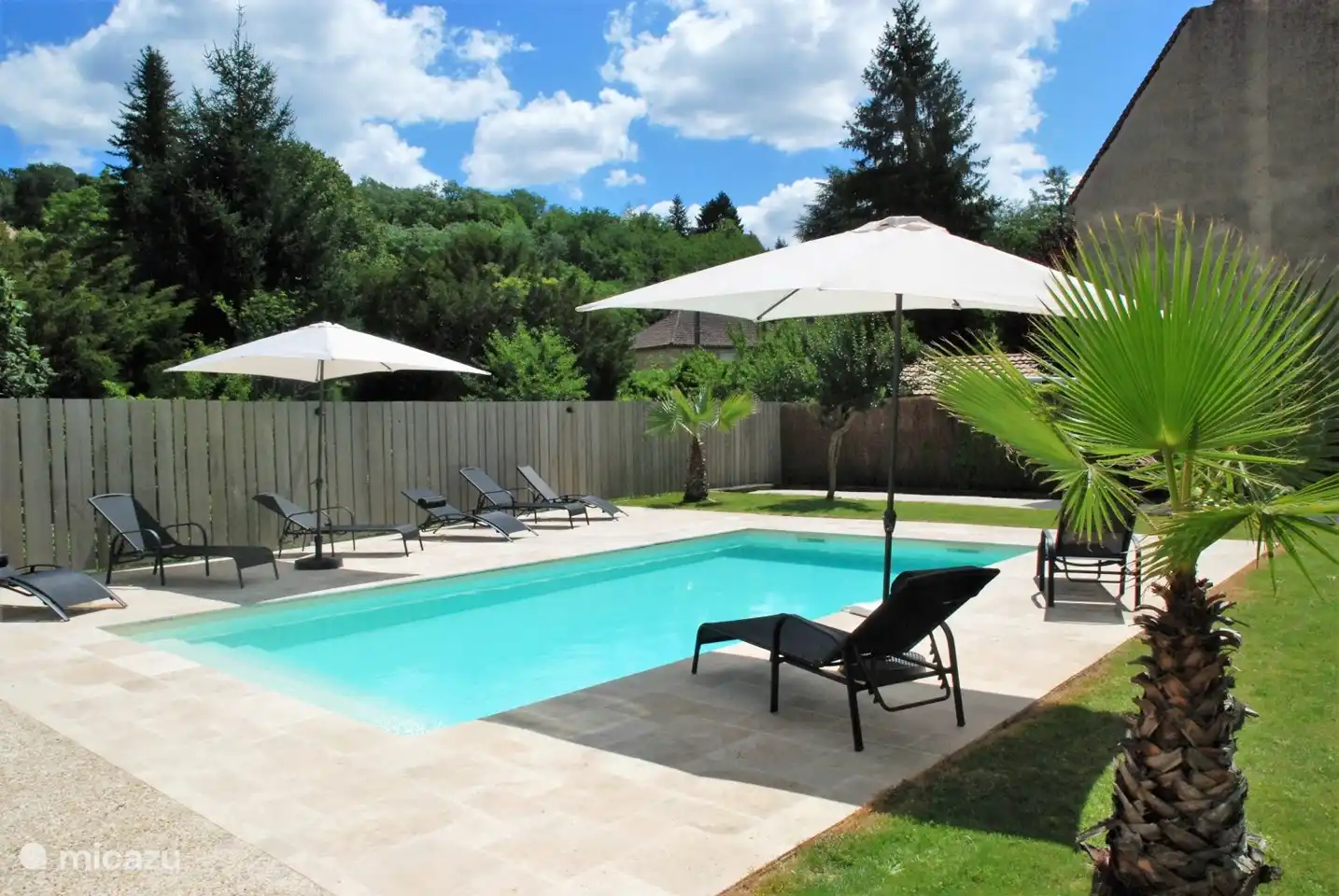 Liegestühle mit Sonnenschirmen rund um den Pool