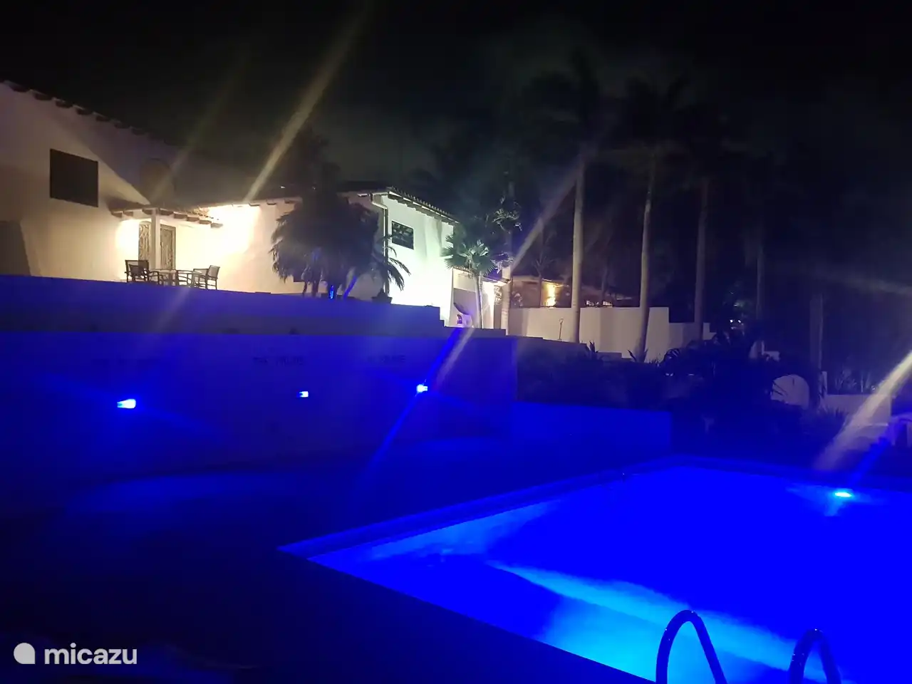 Verlichte zwembad met villa in de nacht