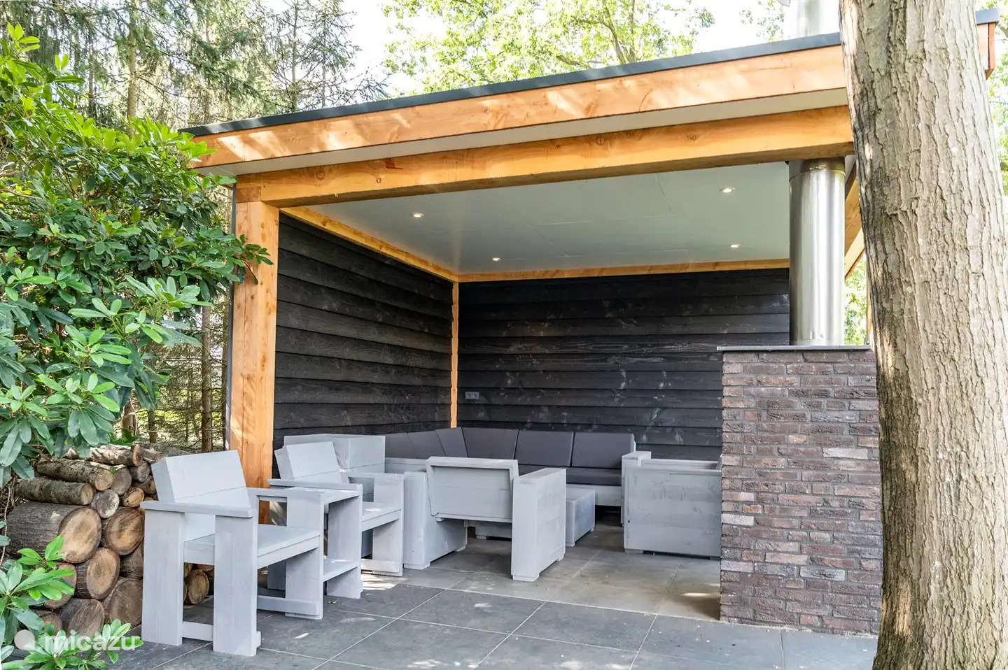 Lounge zitje bestaande uit steigerhouten planken onder overkapping.