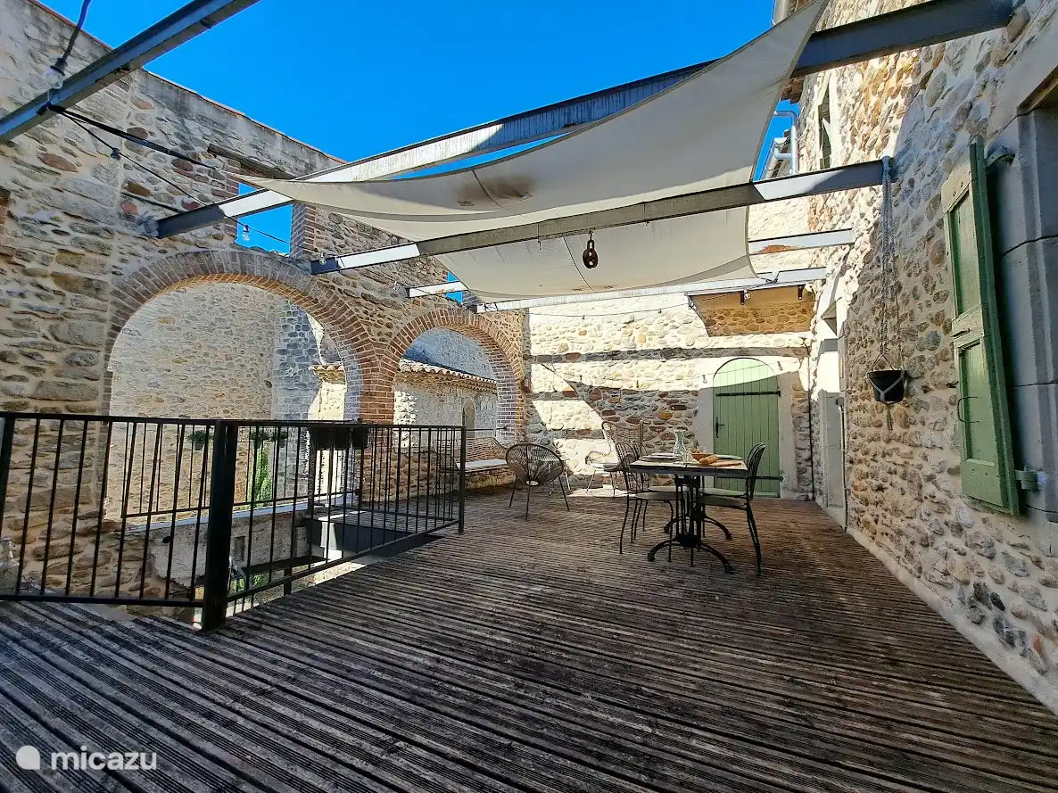 Übersichtsfoto der Terrasse der Gîte Romarin mit Esstisch mit vier Stühlen, Bank und 2 Sesseln.