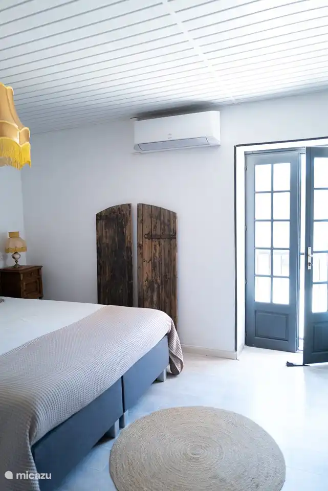 Fenstertüren im Hauptschlafzimmer mit Fensterläden gegen die Sonne und Klimaanlage im Schlafzimmer.