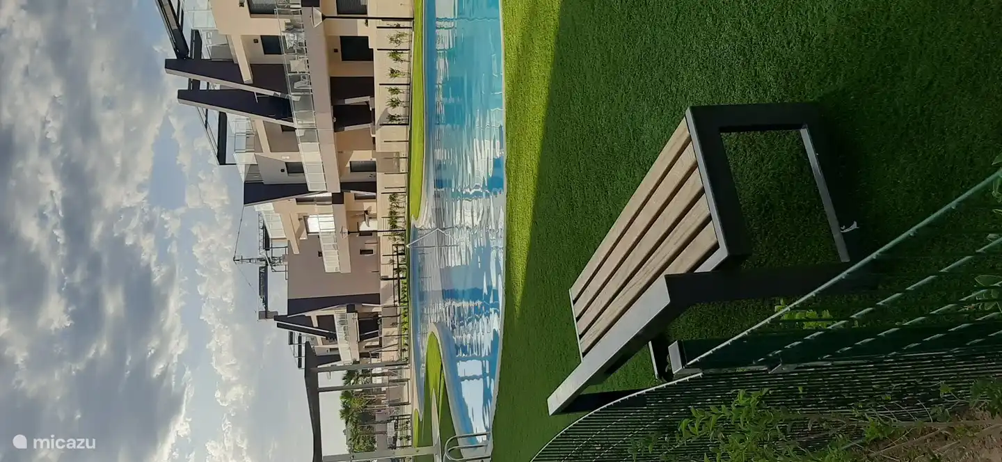 Piscine avec gazon artificiel attenant et zone d’ombre pour les non-baigneurs.