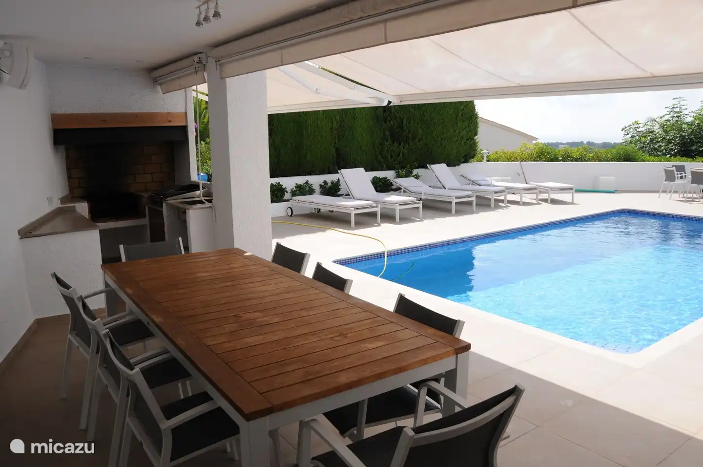 Terrasse couverte avec cuisine extérieure, grande table et réfrigérateur