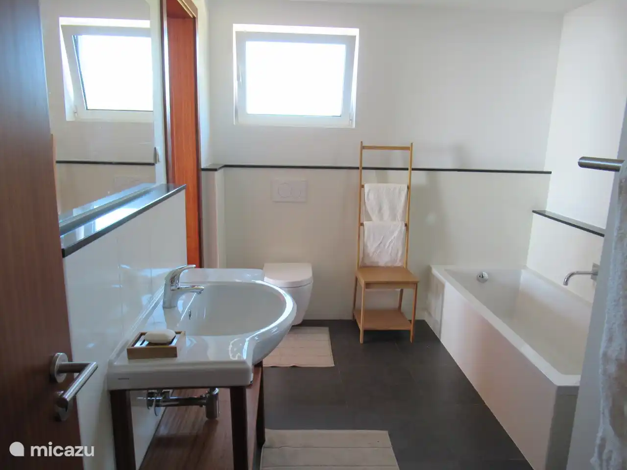 Badezimmer mit Toilette, Badewanne und Regendusche.